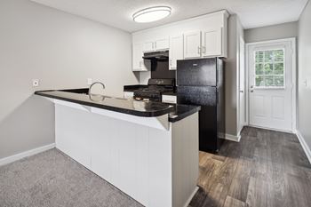 A kitchen with a black countertop and white cabinets.